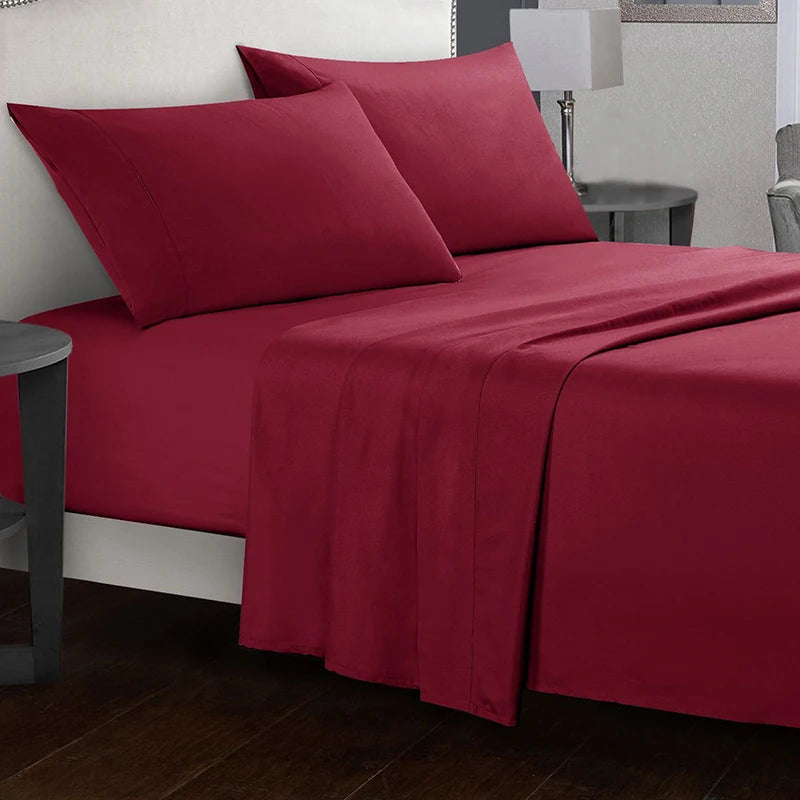 Red bed sheets and pillows on a bed in a bedroom setting.