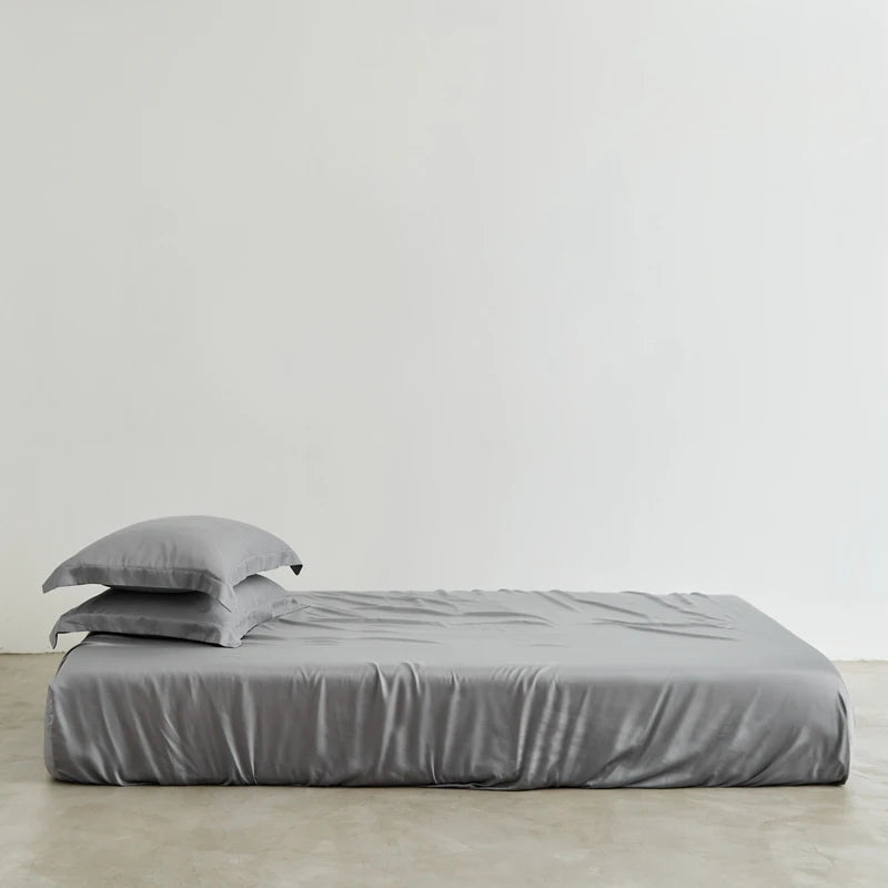 Gray bedding set on a bed against a plain background