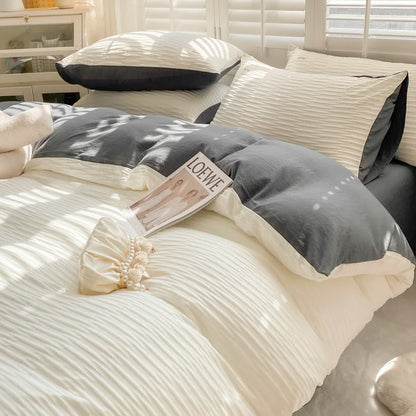 Gray and white bedding set on a bed with a LOEWE magazine.