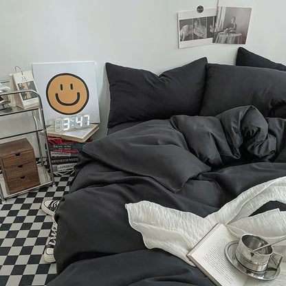 Black bedding set on a bed in a room with a checkered floor and books.