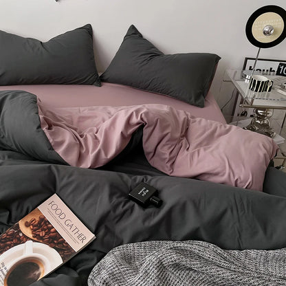 Bed with gray and pink bedding, a book, and a small clock on a nightstand.