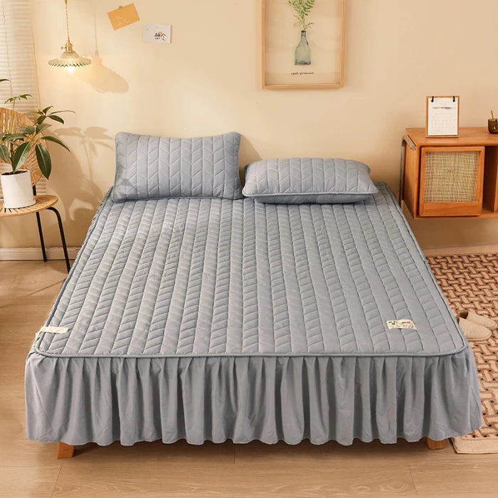 Gray quilted mattress cover on a bed in a bedroom setting