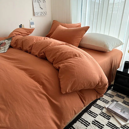 Bed with orange bedding and pillows in a room with a window and decor items.