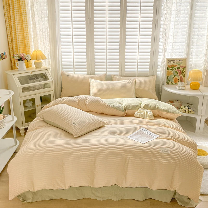 Beige bedding set on a bed in a well-lit bedroom with curtains and shelves.