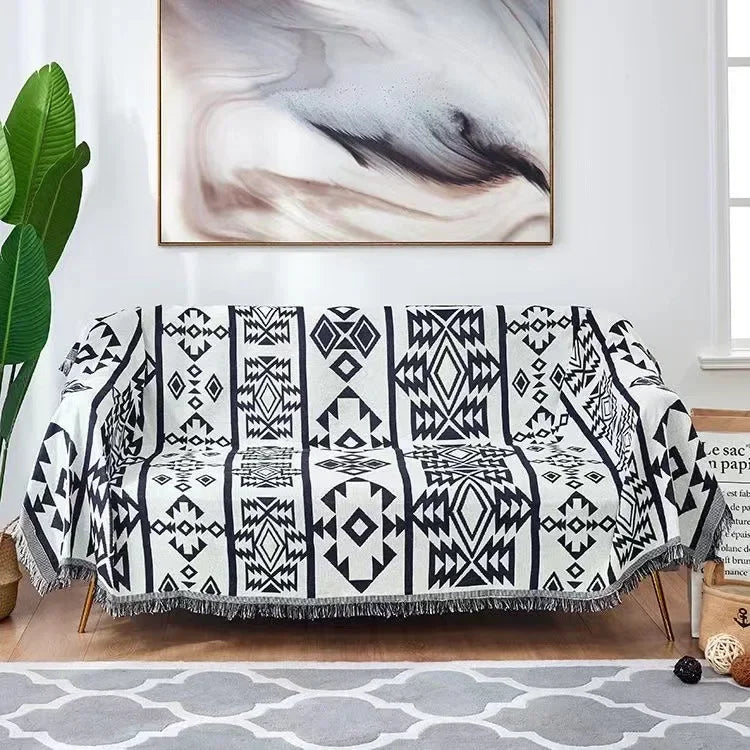 Black and white patterned throw blanket draped over a sofa in a living room setting.