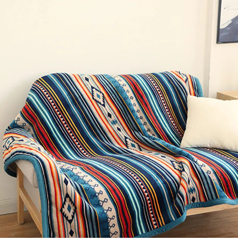 Colorful patterned blanket draped over a chair in a room with a white wall and a small table.