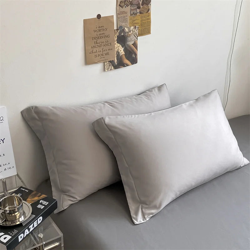 Two gray pillows on a bed with a minimalistic room setting.