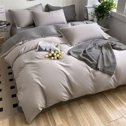 Gray bedding set on a bed with a wooden floor and decorative items.
