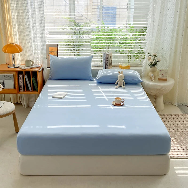 Blue mattress cover on a bed in a bright bedroom with window blinds and decor.