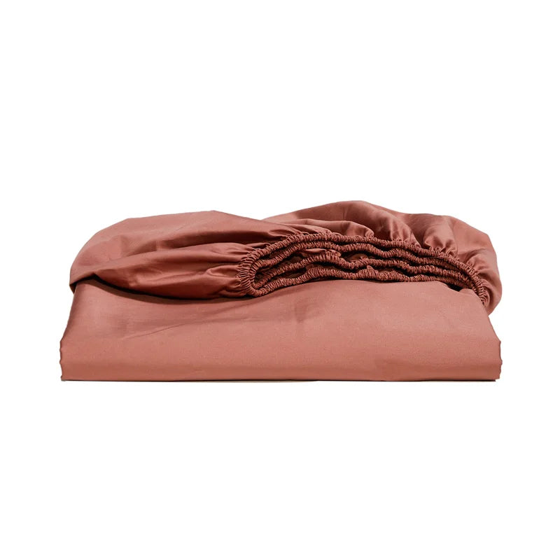 Folded terracotta-colored fitted sheet on a white background
