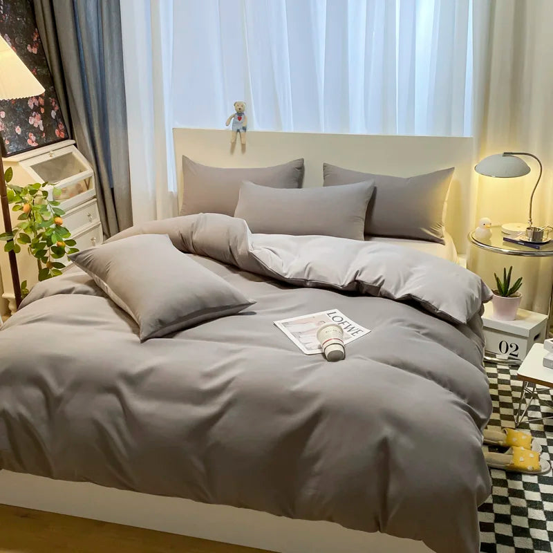 Gray bedding set on a bed in a bedroom with decor elements.