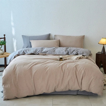 Neatly made bed with beige and gray bedding in a room with light blue walls.