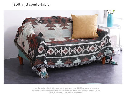 Patterned throw blanket draped over a sofa with a pillow in a room setting.