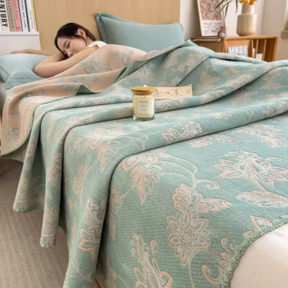 Woman lying on a bed with a floral-patterned comforter, candle, and books in the background.