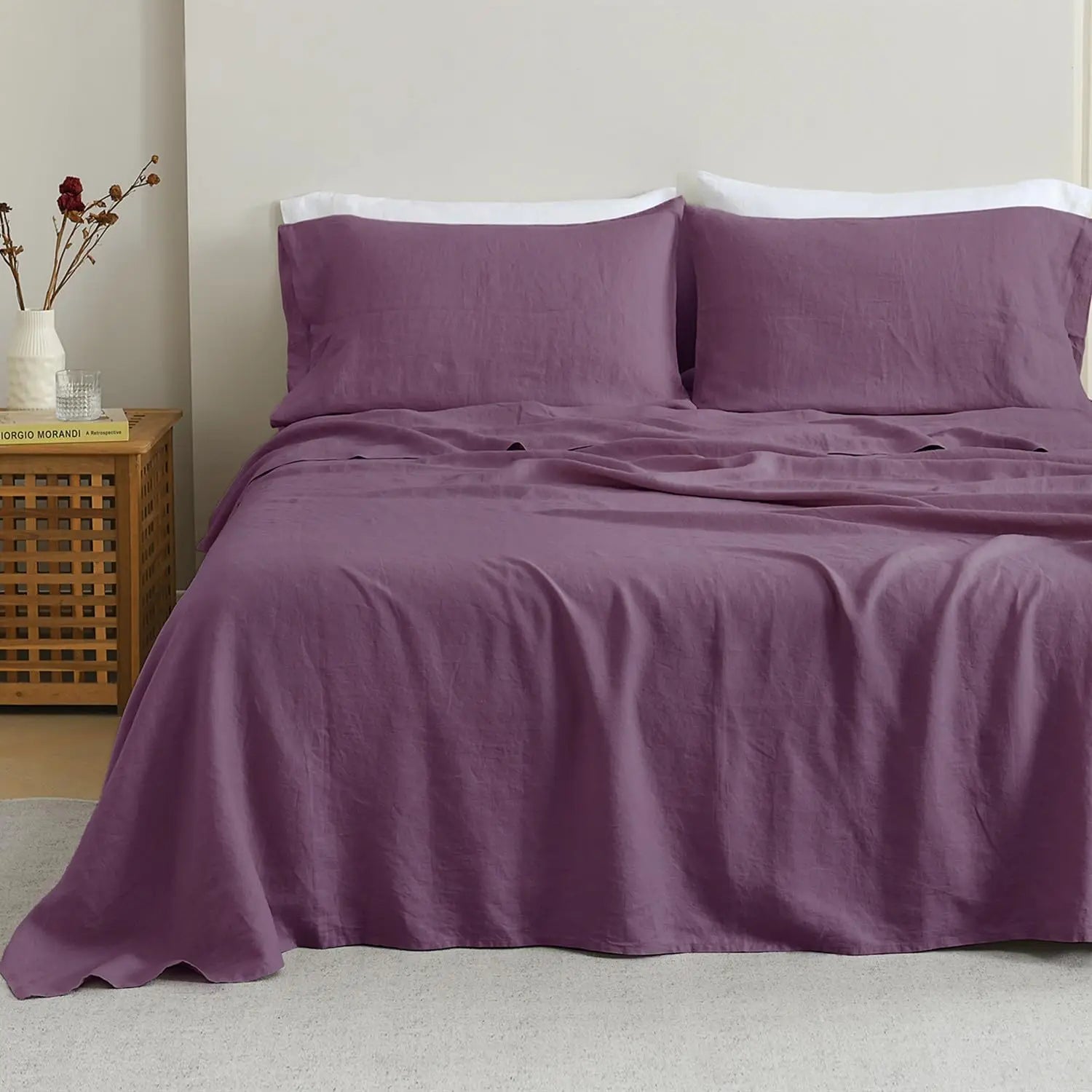 Purple bedding set on a bed with a wooden nightstand in the background.