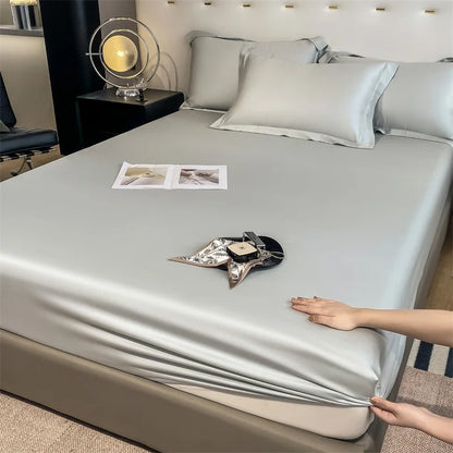 Person adjusting a silver satin sheet on a bed in a bedroom setting.