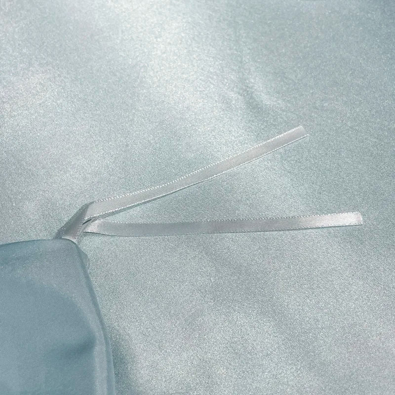 Clear ribbon being cut with scissors on a light blue fabric background