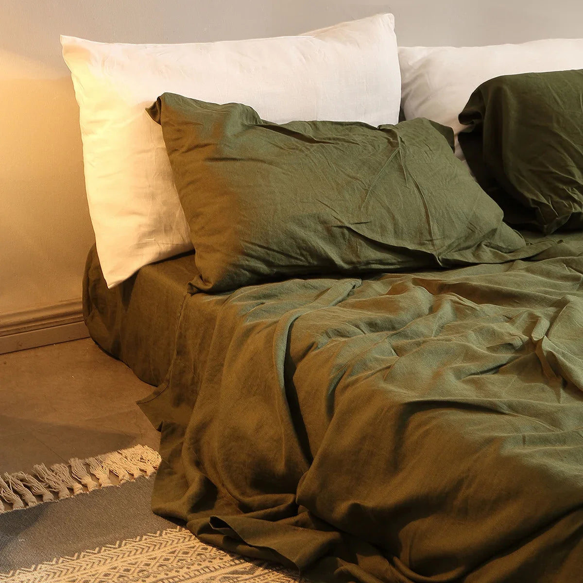 Bed with green bedding and white pillows in a bedroom setting