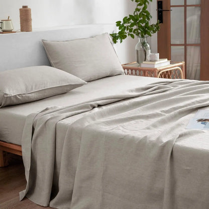 Beige bedding set on a bed with a side table and plant in the background