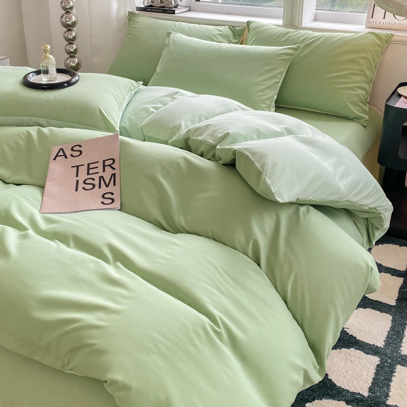 Light green bedding set on a bed with a pink book titled 'Asterisms' in a bedroom setting.