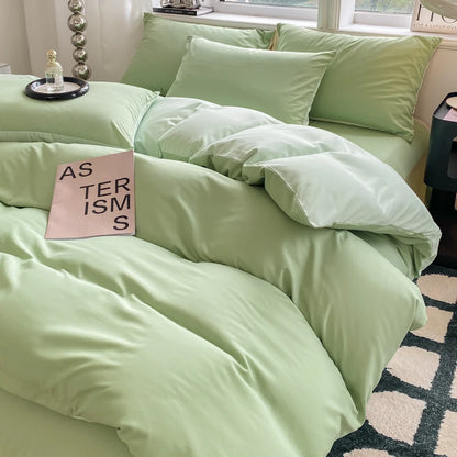 Light green bedding set on a bed with a pink book titled 'Asterisms' in a bedroom setting.