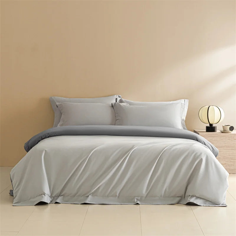 Gray bedding set on a bed in a room with a beige wall and wooden nightstand.