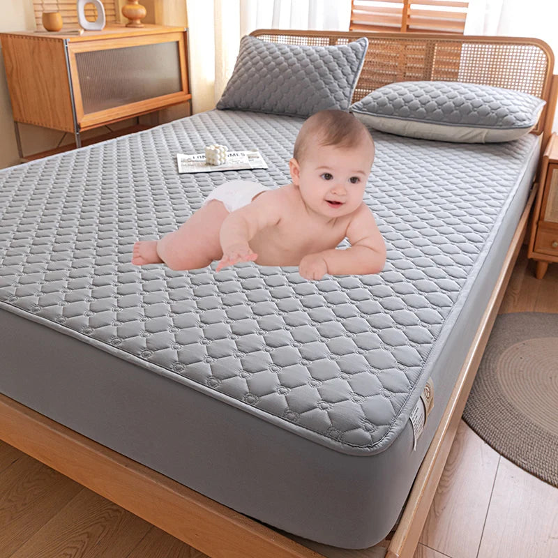 Baby lying on a gray mattress cover in a bedroom