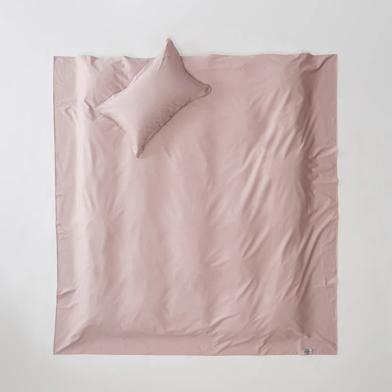 Pink satin sheet set with a pillow on a light gray background