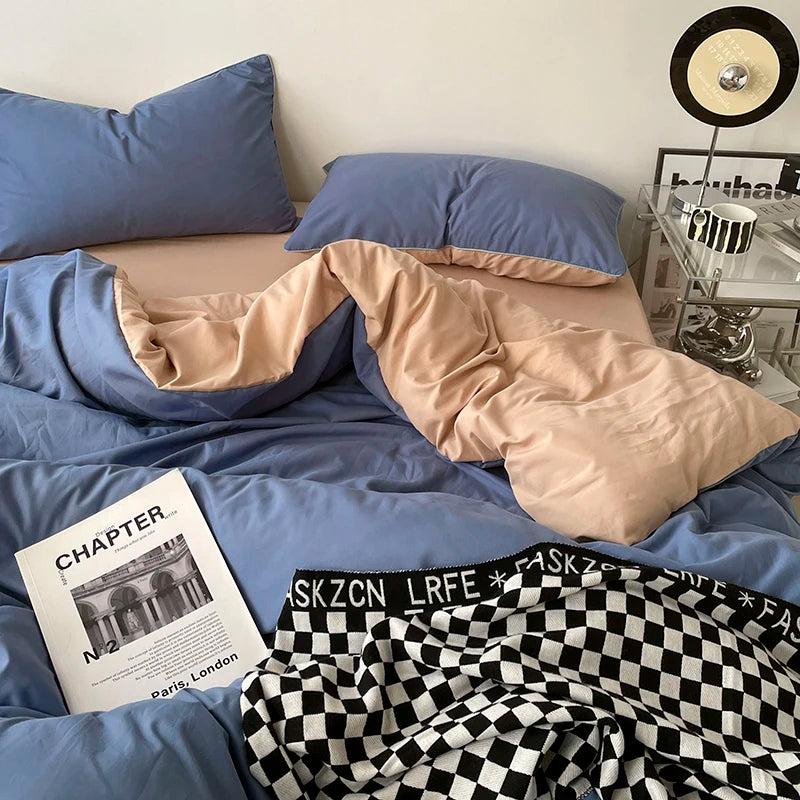 Blue bedding with beige comforter and checkered blanket on a bed, with a magazine and underwear visible.
