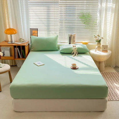 Bed with green fitted sheet and pillows in a bright bedroom