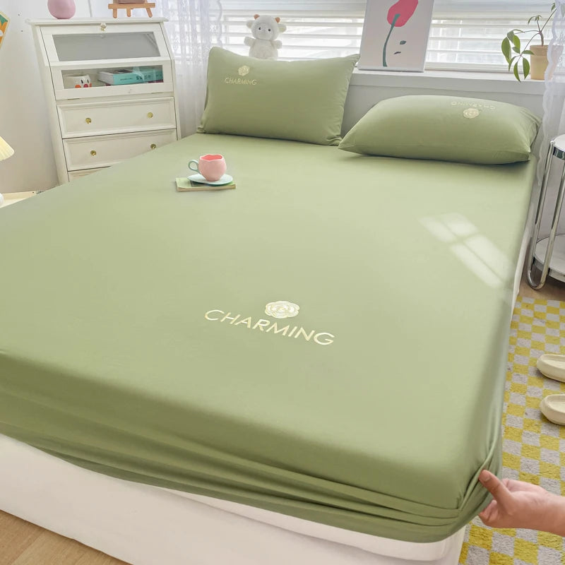 Green bed sheet with 'Charming' branding on a bed in a bedroom setting.
