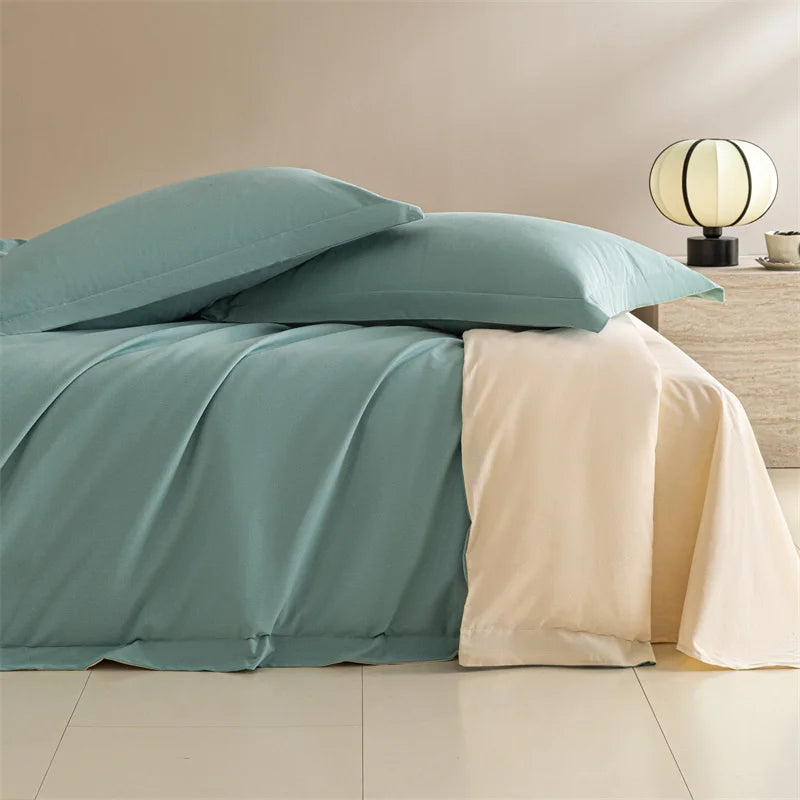 Teal and beige bedding set on a bed with a lamp in the background.