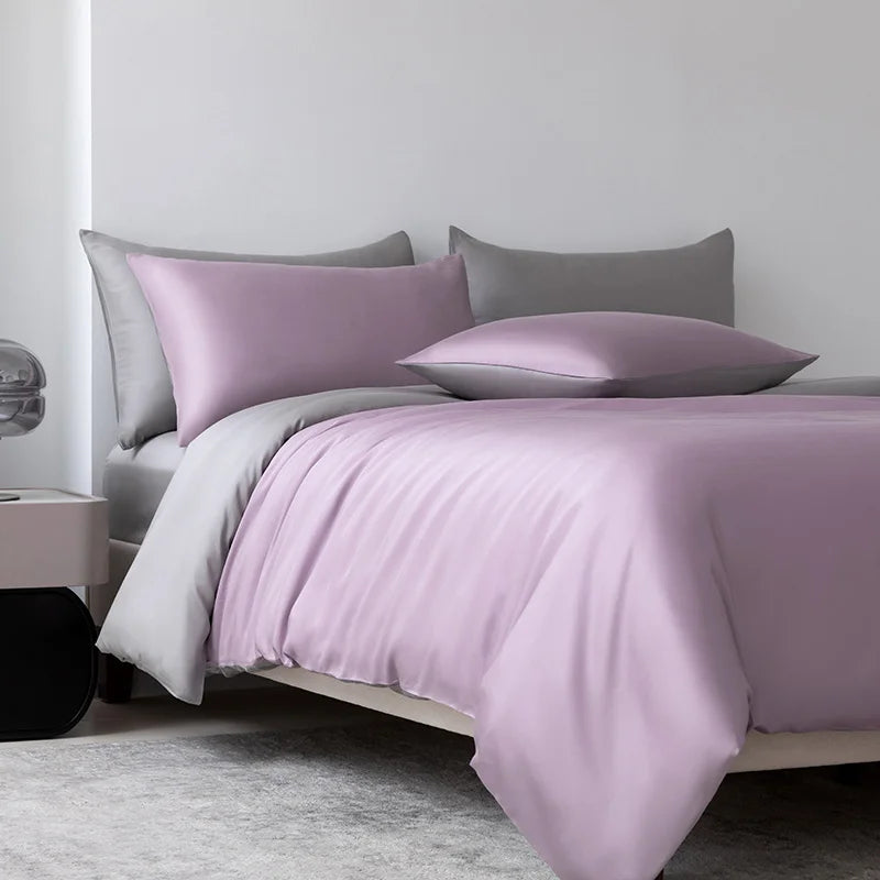 Bed with purple bedding and gray pillows in a minimalistic room.