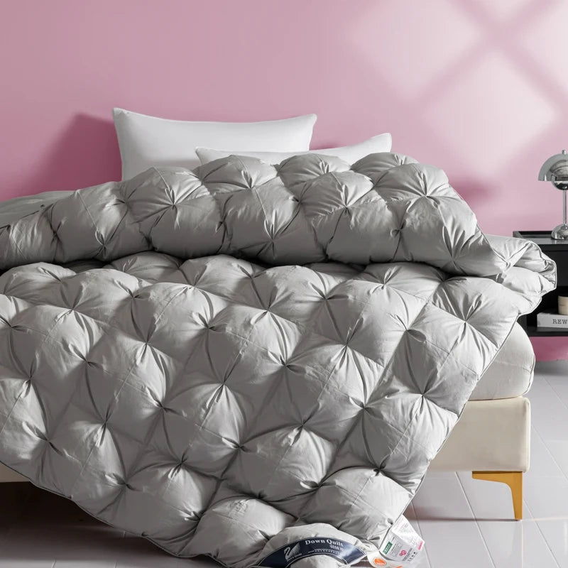 Gray quilted comforter on a bed with a pink wall in the background