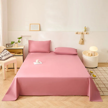 Pink bedspread set on a bed in a bedroom with a nightstand and lamp.