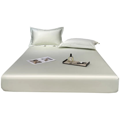 Silky satin sheet set on a bed with pillows and a tray.