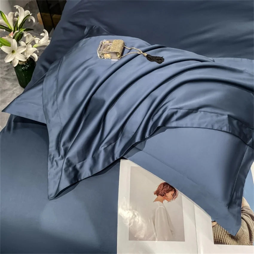 Blue bedding set on a bed with a vase of flowers and a photo frame in the background.