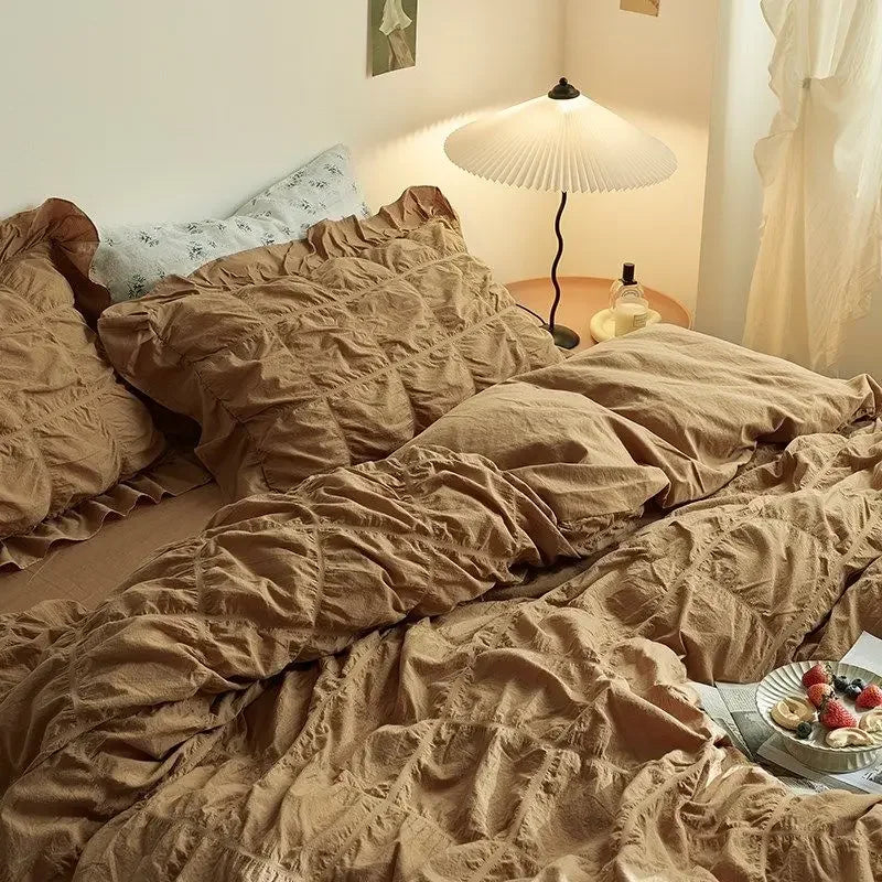Bed with crumpled beige bedding in a softly lit room.