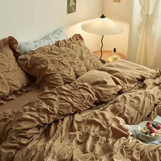 Bed with crumpled beige bedding in a softly lit room.