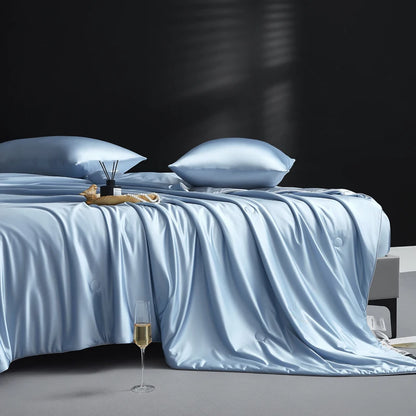 Blue satin bedding set on a bed with a dark background