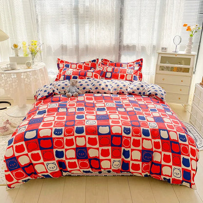Bed with colorful checkered bedding featuring cartoon cat faces, in a bright room.