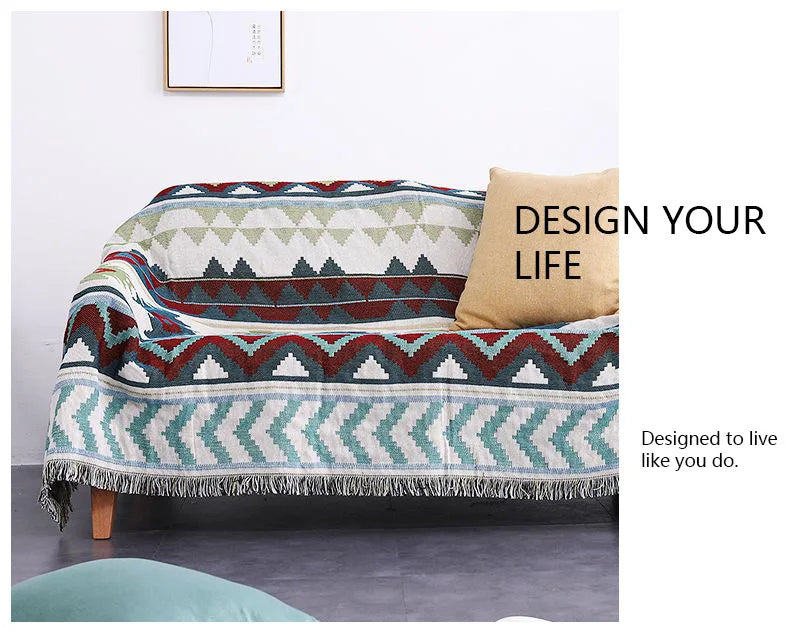 Geometric patterned throw blanket on a sofa with motivational text 'Design Your Life' and 'Designed to live like you do.'