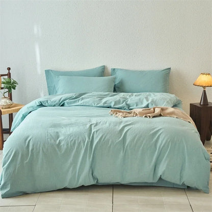 Teal bedding set on a bed in a bedroom with a lamp and plant.