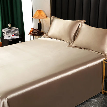 Beige satin bedding set on a bed with a lamp and books in the background.