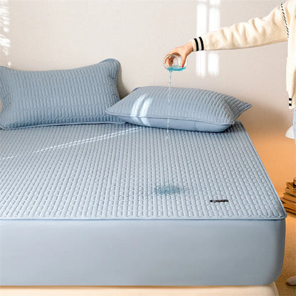 Blue quilted mattress cover on a bed with a hand pouring water onto it.