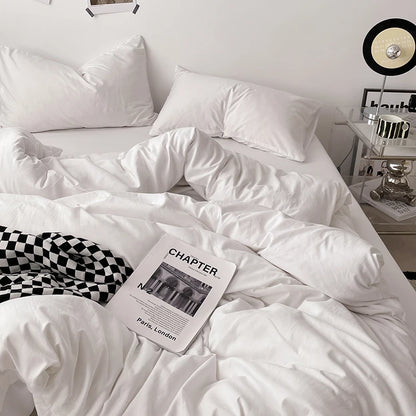 White comforter on a bed with a book titled 'Chapter' in a bedroom setting.