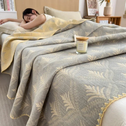 Person sleeping under a patterned blanket with a candle on a nightstand.