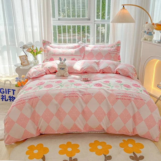 Pink and white checkered bedspread with floral patterns on a bed in a bright room.