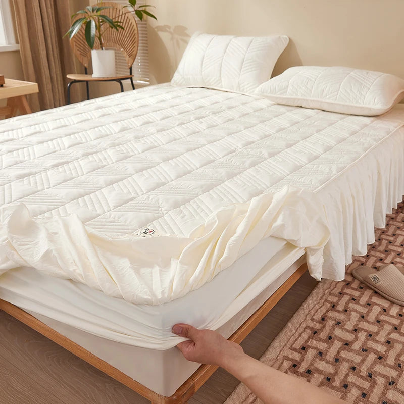 White mattress cover being fitted onto a bed in a bedroom setting.