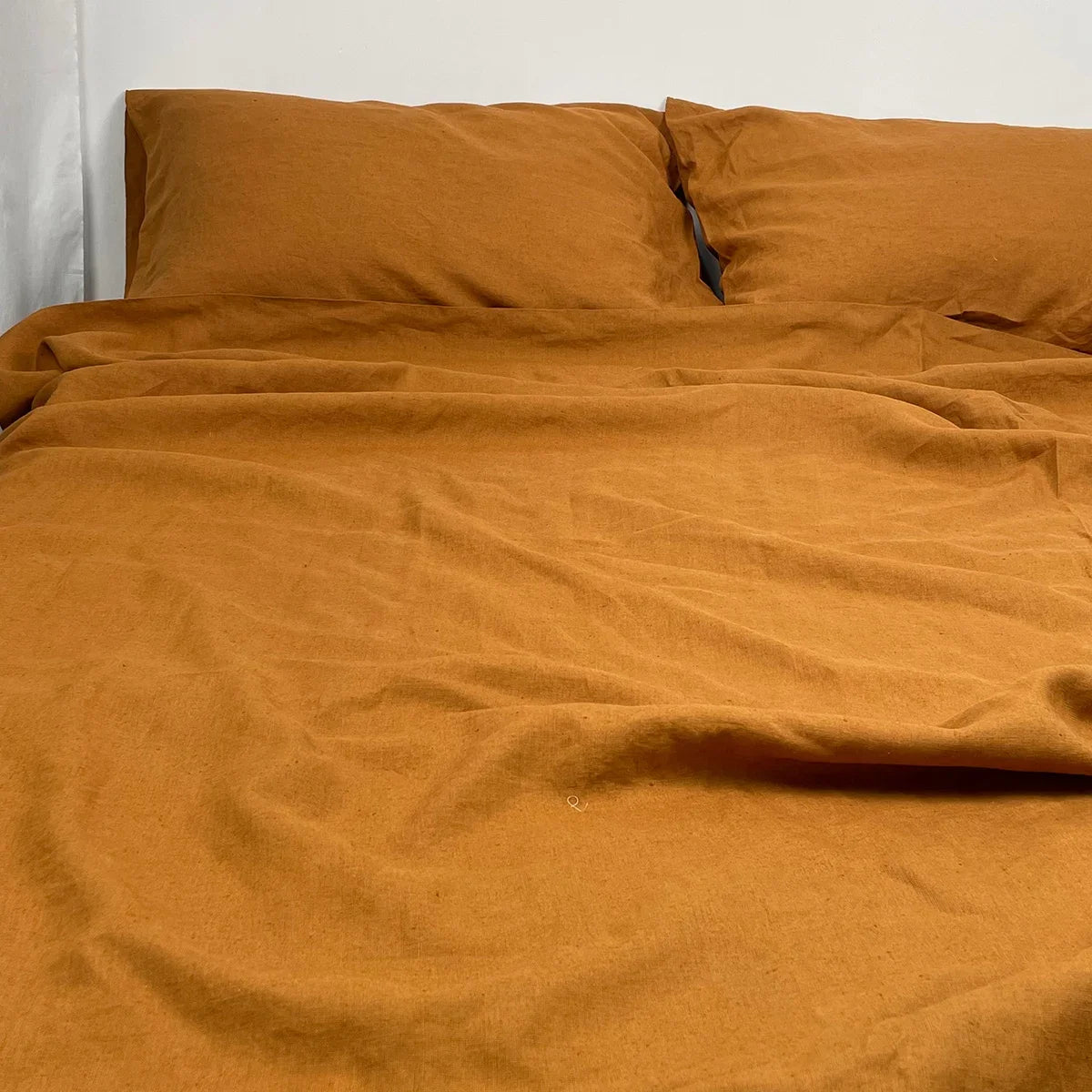 Brown bedspread and pillows on a bed against a white wall